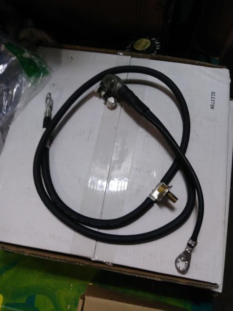 1996 Ford Bronco - A black battery cable with ring terminals is coiled on top of a cardboard box. The cable has text printed on it that reads "JULIAN ELECTRIC…