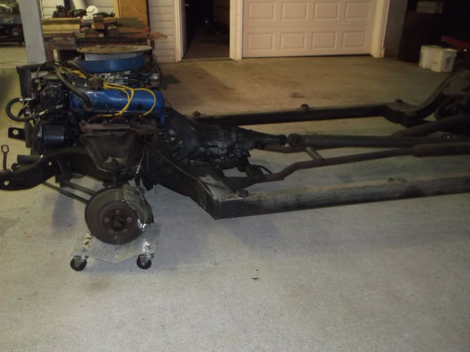 Vehicle chassis with engine and front brake assembly on a dolly.