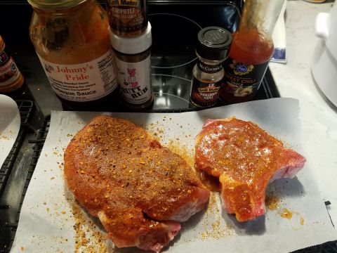 2018 Ford Bronco - Two raw pork chops seasoned with a reddish-brown spice rub are placed on a sheet of parchment paper. Several bottles of barbecue sauce and…