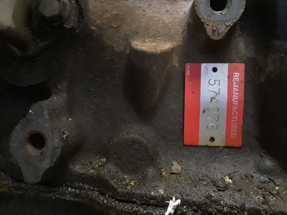 Remanufactured tag with number 574076 on a greasy engine block.