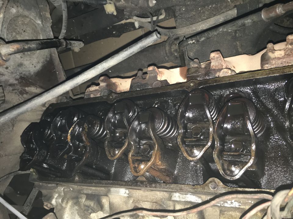 Close-up of engine valve train with oil-covered rocker arms.
