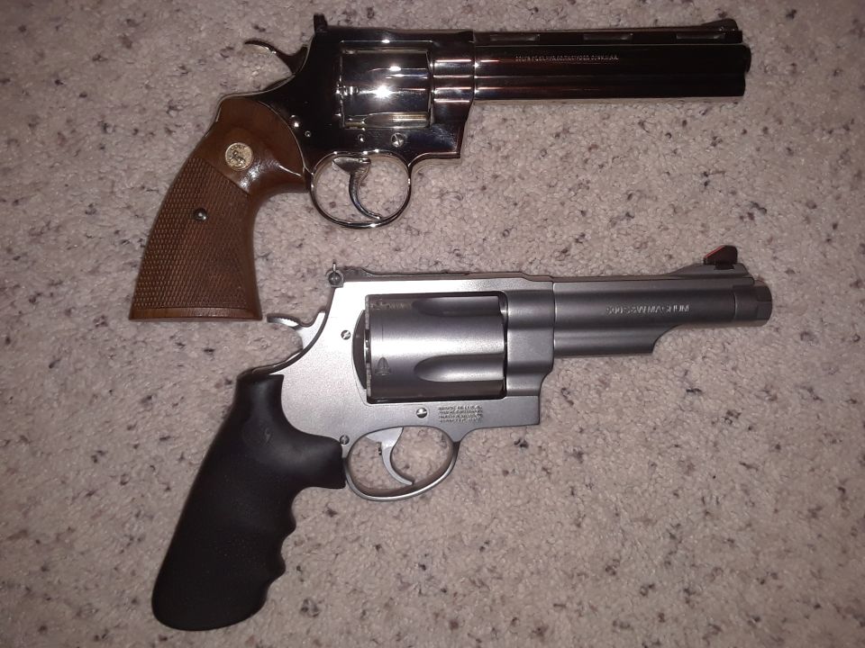 Two revolvers, one blued with brown grips, one silver with black grips, on a carpet.