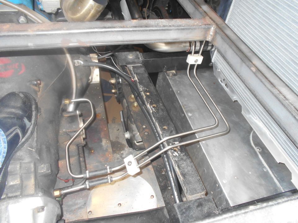 Undercarriage of a vehicle with metal tubing and engine parts visible.
