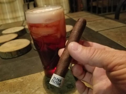 2018 Ford Bronco - A hand holds a cigar with a band that reads "PAPAS FRITAS" next to a glass of red liquid with ice and foam. In the background, wooden coast…