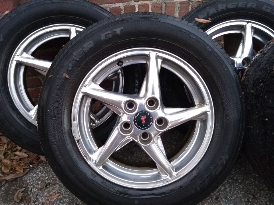 Three chrome Pontiac wheels with tires, showing the Pontiac logo on the center caps.