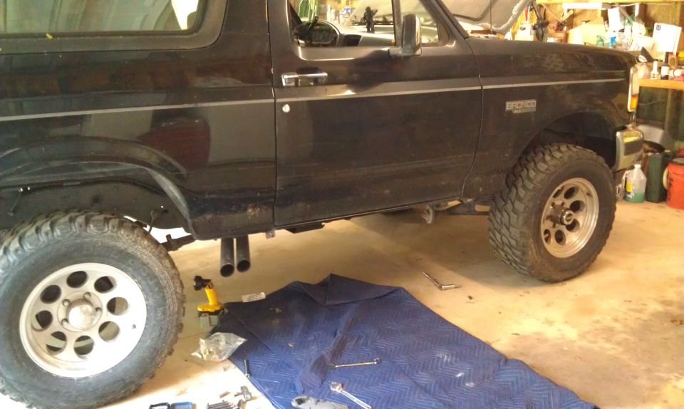 Black Ford Bronco side view with large tires and dual exhaust.