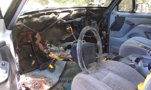 1995 Ford Bronco - The interior of a vehicle is shown with the dashboard removed and the steering wheel exposed, indicating disassembly or repair work.