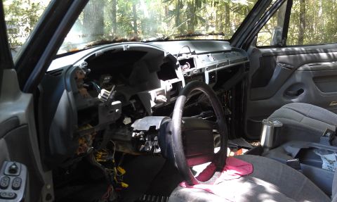 1995 Ford Bronco - The interior of a vehicle is shown with the dashboard disassembled, exposing wiring and internal components.