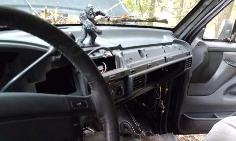 1995 Ford Bronco - Interior view of a vehicle's dashboard with parts removed, revealing wiring and a decorative figurine.