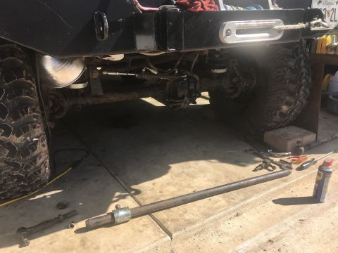 1989 Ford Bronco - Vehicle undercarriage repair, showing steering linkage components removed and laid out on the concrete.