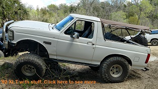 1992 Ford Bronco - A lifted 1992 Ford Bronco with off-road modifications sits parked outdoors, with another vehicle visible in the background.