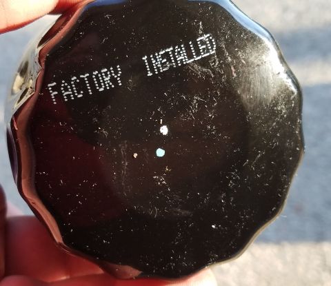2000 Ford Crown Victoria - A close-up view of a black oil filter with white lettering indicating it was factory installed.