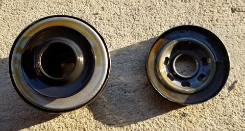 2000 Ford Crown Victoria - Two oil filters are shown side-by-side on a concrete surface, with visible oil residue on both parts.