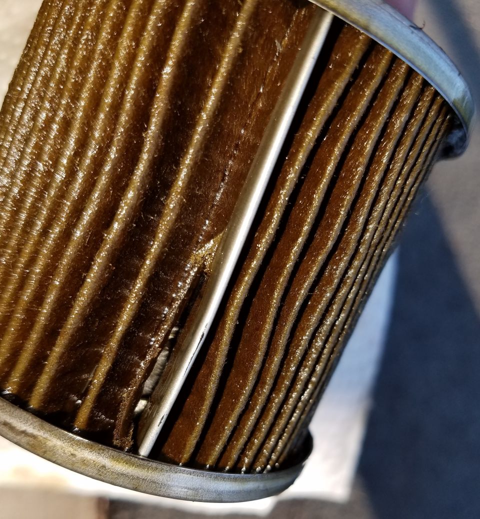 Close-up of a used oil filter with dirty, pleated filter media