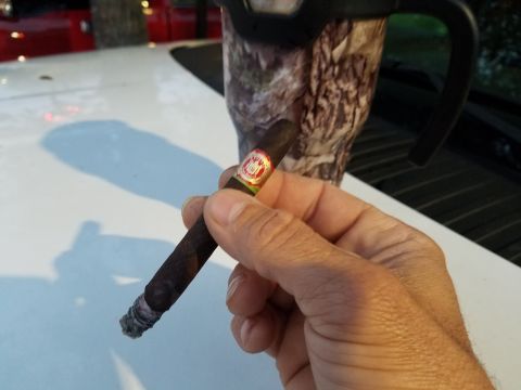 2018 Ford Bronco - A hand holds a lit cigar, with a camouflage cup visible behind it. The image also shows a watermark for Supermotors.net.