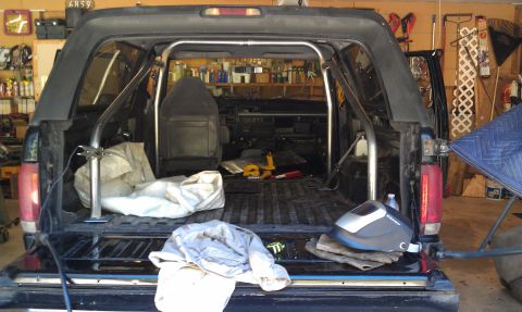 1995 Ford Bronco - Interior view of a black Ford Bronco, modified with a roll cage and other equipment.