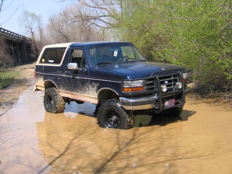 1995 Ford Bronco - This 1995 Ford Bronco is navigating through a muddy trail with its tires submerged.