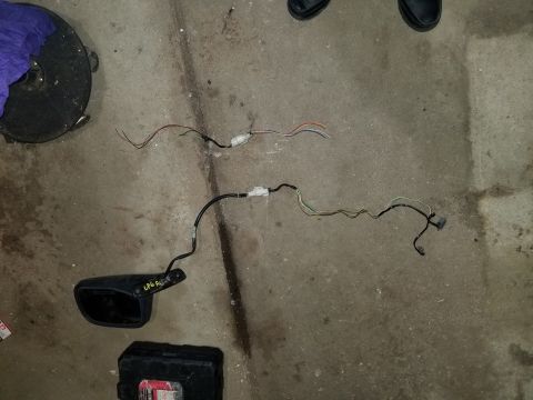 1995 Ford Bronco - A car side mirror and its wiring harness are laid out on a concrete surface.
