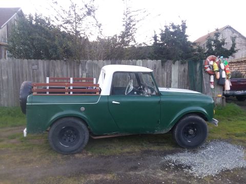 1991 Ford Bronco - This green pickup truck features wooden bed rails and a white roof, seen from the side.