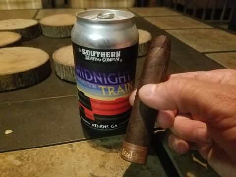 2018 Ford Bronco - A hand holds a cigar next to a can of Midnight Train Porter beer.