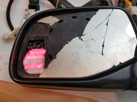 1967 Ford Bronco - Side mirror assembly shows significant damage with a cracked mirror and exposed internal components.