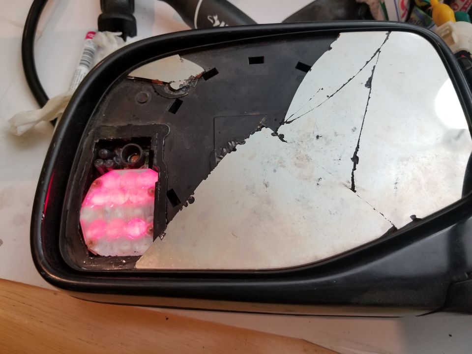 Broken side mirror assembly with cracked glass and exposed pink foam