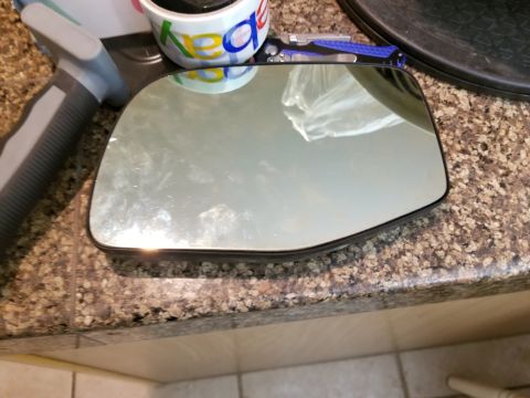 1967 Ford Bronco - Side mirror glass is shown resting on a speckled countertop surface.