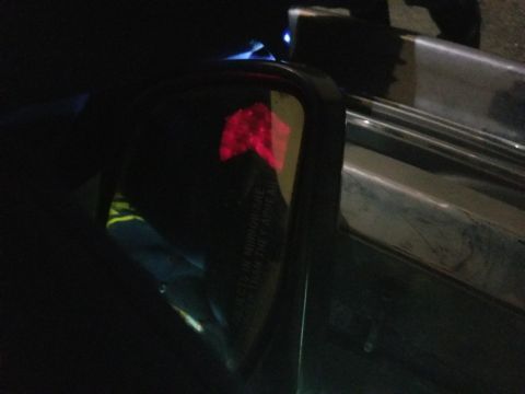 1995 Ford Bronco - Close-up of a vehicle's side mirror, a red arrow sticker and some text on the glass.