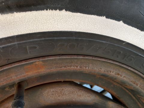 1987 Ford Crown Victoria LTD - Close-up of a tire and rusty wheel rim with size information visible on the sidewall.
