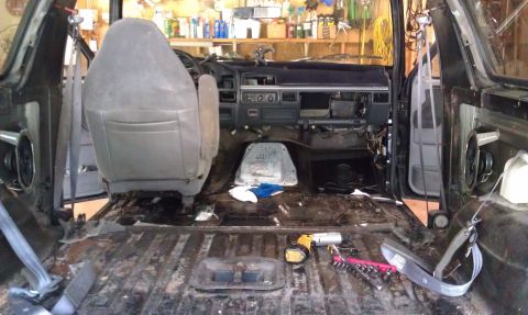 1995 Ford Bronco - The interior of a vehicle is shown with the floor stripped and dashboard partially dismantled, indicating ongoing work.