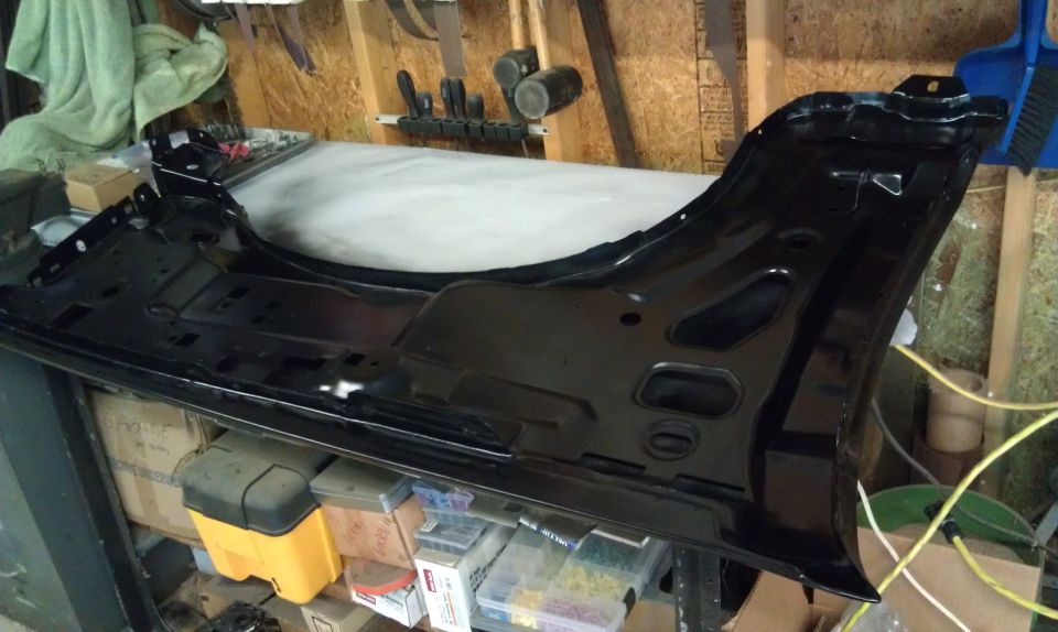 Black metal fender assembly with mounting brackets and cutouts, resting on a workbench