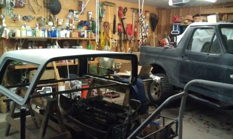 1995 Ford Bronco - A Ford Bronco is parked in a garage next to its detached roof, which is being worked on.