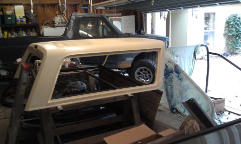 1995 Ford Bronco - A close-up view of a car part, likely a headlight, resting on a workbench in a cluttered garage.