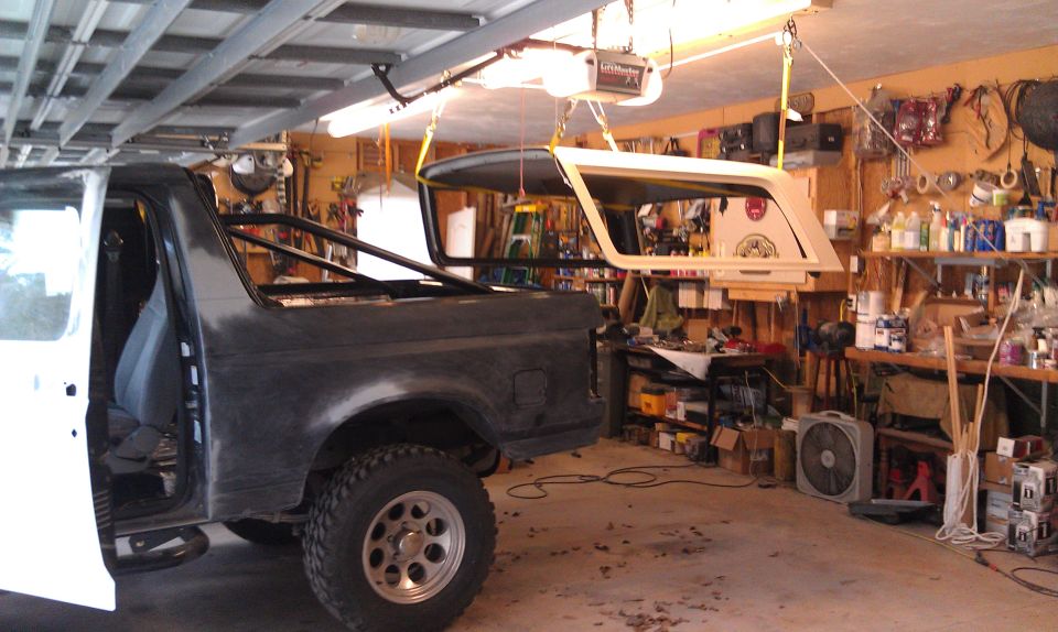 Dark gray Ford Bronco SUV, side view, parked indoors with warm lighting
