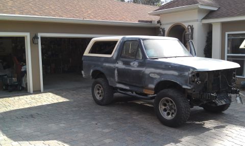 1995 Ford Bronco - Ford Bronco with a white topper parked in front of a garage.