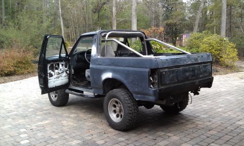 1995 Ford Bronco - This 1995 Ford Bronco is prepped for paint with its doors open and a roll cage visible.