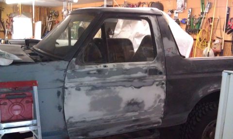 1995 Ford Bronco - This Ford Bronco is undergoing bodywork, with primer and filler visible on the door panel.