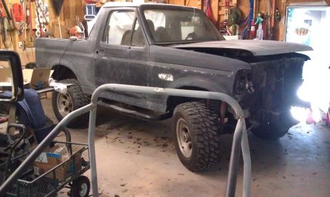 1995 Ford Bronco - This Ford Bronco is undergoing repairs in a garage, with its front end missing parts.