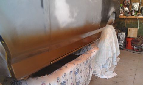 1995 Ford Bronco - A vehicle's side panel is shown in a garage, partially covered by drop cloths during what appears to be a painting or repair process.