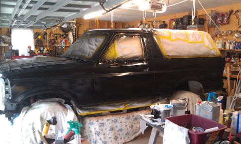 1995 Ford Bronco - A black Ford Bronco is being prepped for painting in a cluttered garage environment.