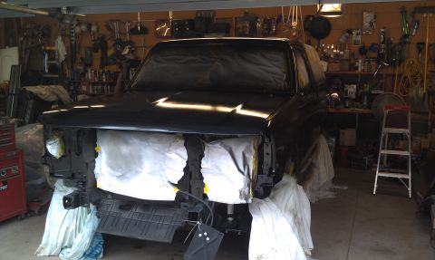 1995 Ford Bronco - A black SUV is being prepped for painting inside a cluttered garage, with its front end covered.
