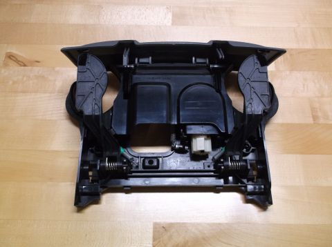 1995 Mercury Grand Marquis - This black plastic center console trim piece features springs and levers, likely for a cup holder or storage compartment.