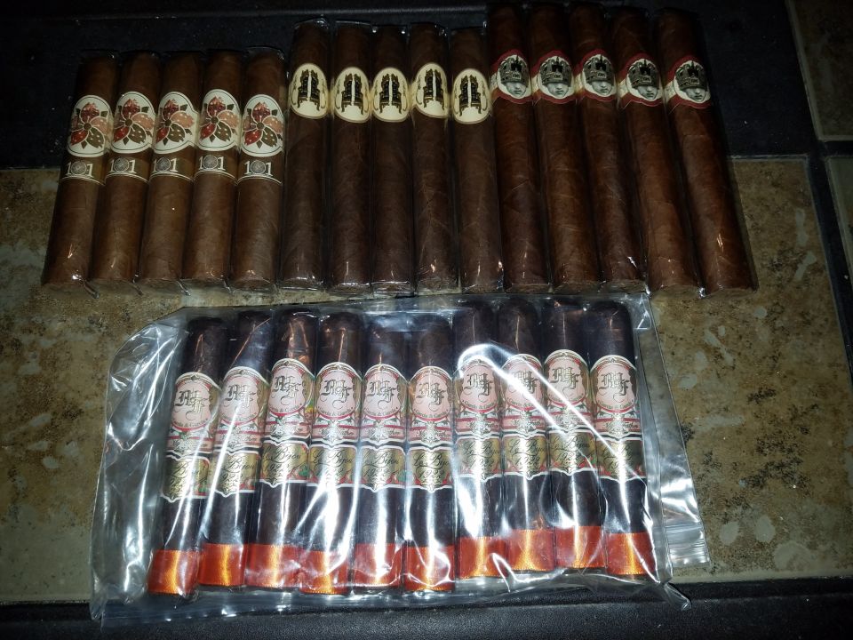 Two rows of cigars, some in plastic packaging, on a tiled surface