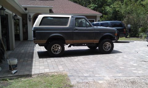 1995 Ford Bronco - This Ford Bronco is parked in front of a garage with a second SUV behind it.