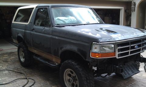 1995 Ford Bronco - This Ford Bronco is undergoing some work, with its front bumper removed and the paint looking rough.