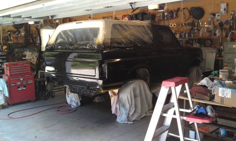 1995 Ford Bronco - A Ford Bronco is covered in plastic sheeting in a garage, likely undergoing a paint job.