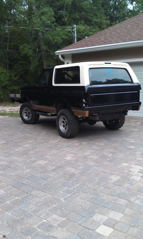 1995 Ford Bronco - This two-tone 1995 Ford Bronco is shown from the rear three-quarter angle, parked on a paved driveway.