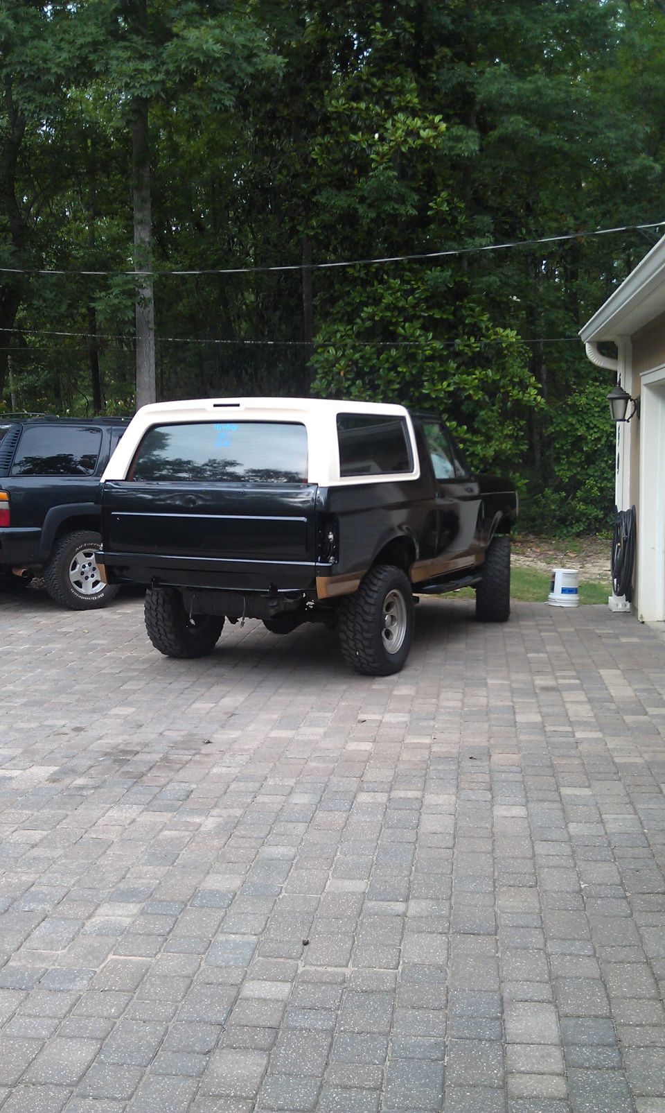 Black Ford Bronco with white top, parked next to a dark SUV