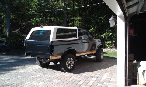 1995 Ford Bronco - This lifted Ford Bronco has a two-tone paint scheme with a dark blue body and a white removable top.