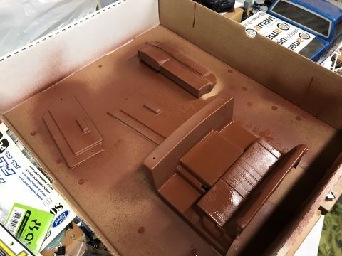 1989 Ford Bronco - Spray painting model car interior parts in a cardboard box.